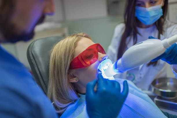 a dentist performing an in-office teeth whitening treatment on a patient