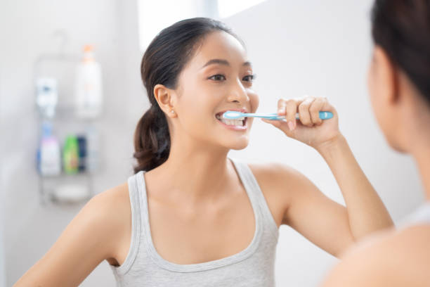 a woman brushing her teeth in front of a mirror